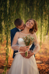 Wedding photo of the bride and groom near the willow tree.