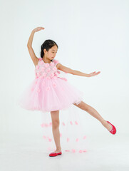 Isolated full body studio shot of little cute pretty Asian ballerina kid wears pink beautiful roses flowers ballet dress and red shoes smiling posing dancing happily in front of white background