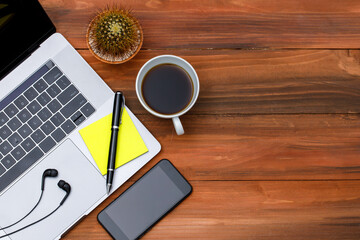 Topview or top down shot of laptop notebook computer with with black coffee in white cup on wood background with copy space. Business idea and creative working concept