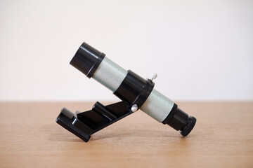 Finderscope, a telescope parts on wooden table. Astronomy lesson exploring parts of telescope.