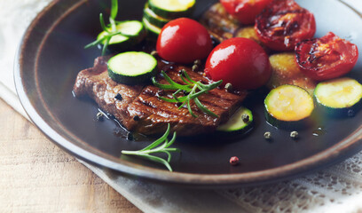Grilled beef steak with tomatoes and fresh herbs. Close up.