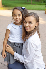 a beautiful young mother hugs her swarthy schoolgirl daughter