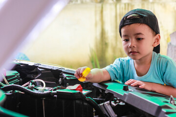 Little child trying to fix broken real car. Dreaming to be auto technician
