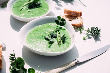Obraz na płótnie Canvas cream soup of green peas in a white plate on a white background