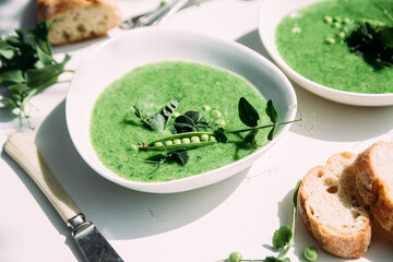cream soup of green peas in a white plate on a white background