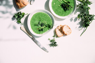 cream soup of green peas in a white plate on a white background