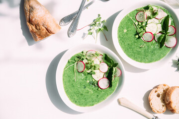 Green cucumber gazpacho in a white plate on a white background