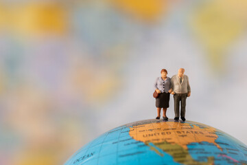 Miniature people Family  Grandfather Grandmother standing on Global world map with happiness using for travel around the world business trip traveler adviser agency or online world wide marketing 