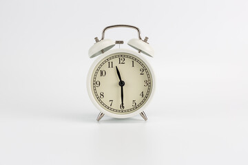 White retro clock alarm clock on white background shows 11:30 am or 11:30 pm or 23:30