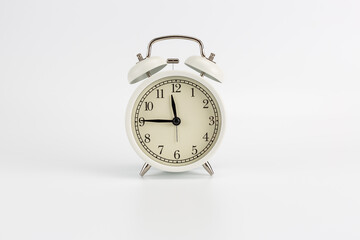 White retro clock alarm clock on white background shows 11:45 am or 11:45 pm or 23:45