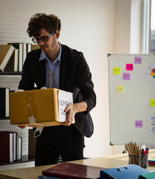 unhappy distressed Caucasian businessman packing his things into a box. He was layoff from the company closed. Financial problem, bankruptcy and unemployment concept