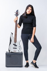 Portrait shot of an attractive young Thai-Turkish teenager standing and holding the bass guitar on...