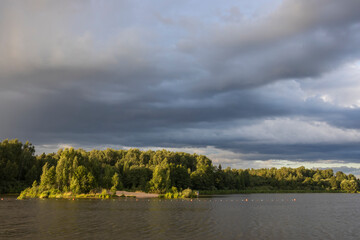 Cloudy sky over the river in the evening. Picturesque landscape with clouds and a river.