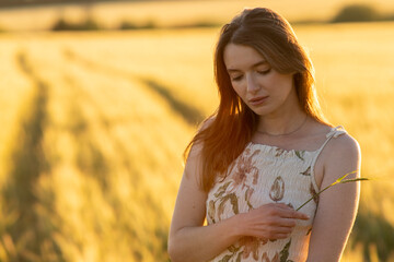 Girl in a dress in a wheat field at sunset