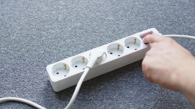 a male hand pulls a white plug out of a junction box and turns it off. 