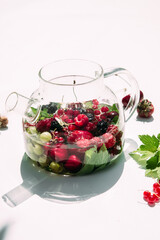 Tea with summer berries in a transparent teapot