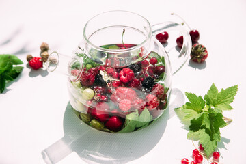 Tea with summer berries in a transparent teapot