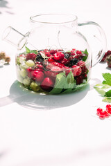 Tea with summer berries in a transparent teapot