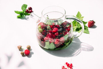Tea with summer berries in a transparent teapot