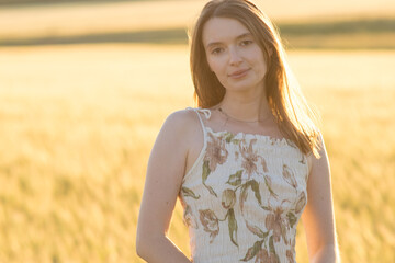 Girl in a dress in a wheat field at sunset