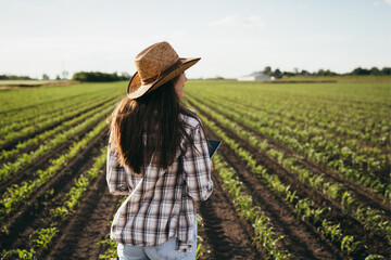 woman farmer walking on corn field - Powered by Adobe
