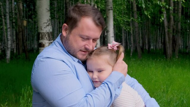 Smiling dad gently hugs his little daughter, 3 years old, enjoying fatherhood. Fathers day. Happy childhood and parenting concept. Child protection