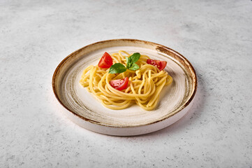 Close up spaghetti pasta with tomato cherry, parmesan cheese and basil on ceramic plate on light background