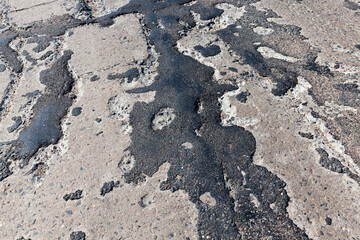 a bad asphalt road that has been repaired many times