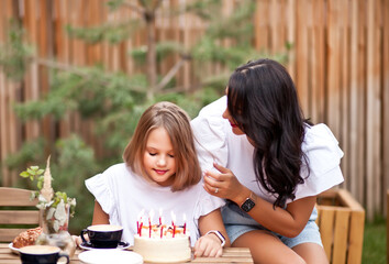 Obraz na płótnie Canvas Happy adorable girl with mom celebrate with birthday cake in cafe terrace. 10 year old celebrate birthday.