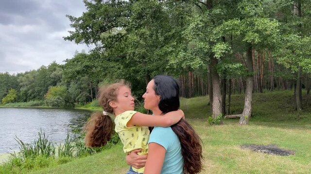 4k Mother Hugs And Kiss Her Daughter In A Park Near River.