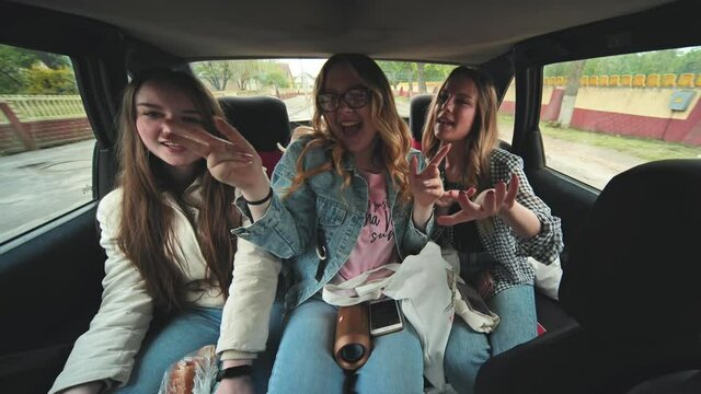Girls dance and sing in the car.