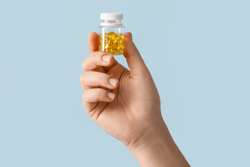Female hand and bottle with pills on color background