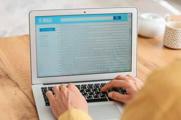 Young man with laptop checking his e-mail at home