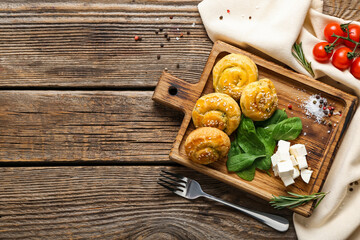 Puff pastry stuffed with spinach and feta cheese on wooden background