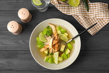 Composition with tasty Sopa de Lima soup on dark wooden background
