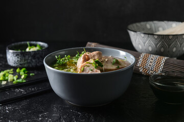 Tasty Chinese soup with chicken in bowl on dark background