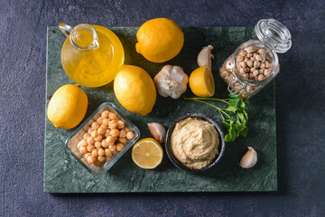 Composition with tasty hummus and ingredients on dark background