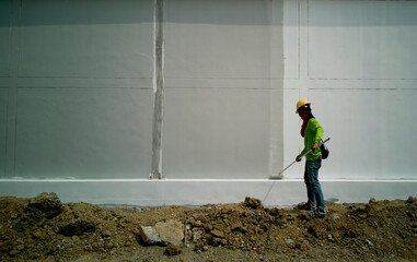 Rear view of painter man looking and painting blank wall, painter is working in white wall, wall is grey color and white color,