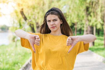Portrait of a young and beautiful Caucasian girl showing thumbs down. Dislike