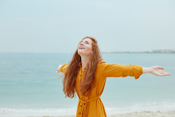Fototapeta na wymiar Enjoy the vacation. Bautiful overjoyed woman with a long red hair on the beach