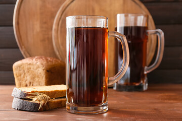 Mugs of fresh kvass on wooden background