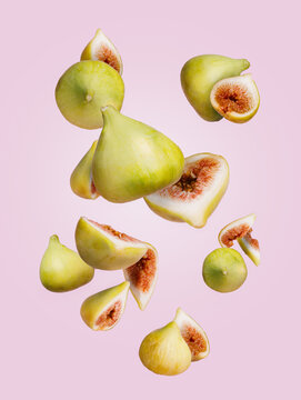 Juicy Green Figs Slices Thrown In The Air Falling Down And Flying Against Pastel Pink Background. Creative Food Concept. Motion With Tropical Autumn Fruit. Vegetarian Diet Idea.