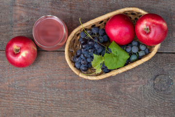  a glass of rose wine, apples and a bunch of grapes.