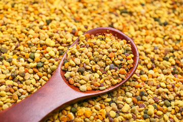 Heap of bee pollen with spoon, closeup