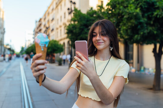 Smiling woman taking photo of ice cream on smartphone