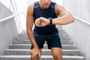 sport, technology and healthy lifestyle concept - young man with fitness tracker on city street