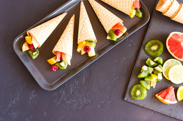fresh chopped fruit in waffle cones. cutting board with fruit on it. top view.