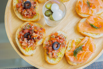 Top view and selective focus of tapas which is small portion appetizer food (smoked salmon, cooked tomato and parma ham on toasted breads) served in european restaurant for sharing before meal.