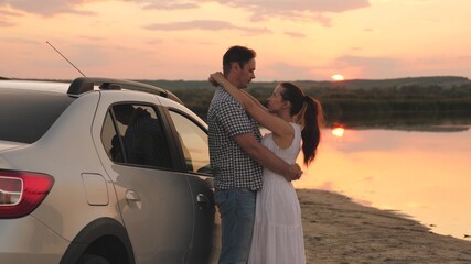 Woman and man hugging at sunset, relationship of two people, happy family, traveling by car, dreaming of being loved, meeting the dawn with a loved one, hugging a woman on the beach in the sun