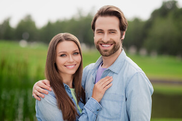 Fototapeta premium Photo portriat young couple smiling embracing walking in green city park wearing jackets